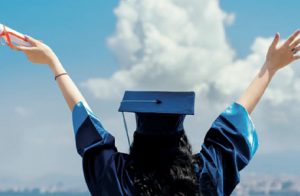 A Young Female & Happy Graduate Student Wearing Academic Dress Holding Degree Certificate On Her Hand.