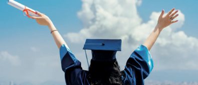 A Young Female & Happy Graduate Student Wearing Academic Dress Holding Degree Certificate On Her Hand.