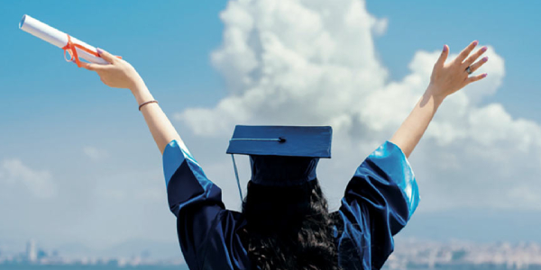 A Young Female & Happy Graduate Student Wearing Academic Dress Holding Degree Certificate On Her Hand.