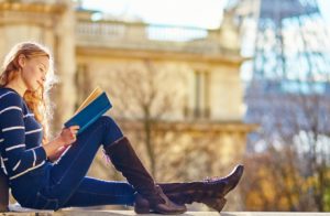 A Young Smiling College Girl Sit In A Place And Studying.