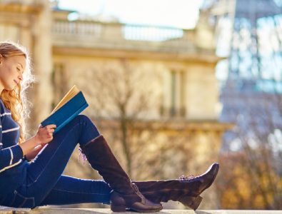 A Young Smiling College Girl Sit In A Place And Studying.