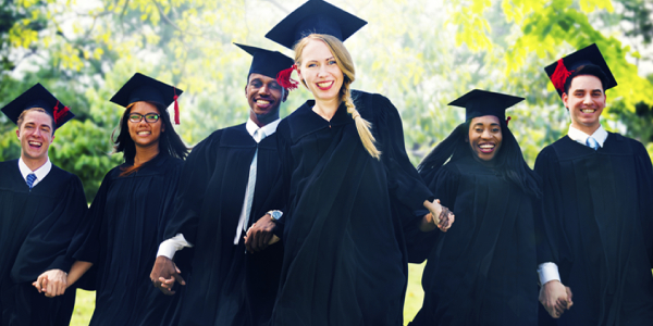 Happy And Young Smiling Graduates In Their Academic Dress.