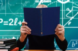 A Person Studying With A Book Hiding His Face.