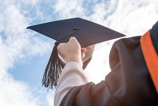 Successful Graduate In Academic Dress Holding Diplomas And Thrown The Cap In Air.