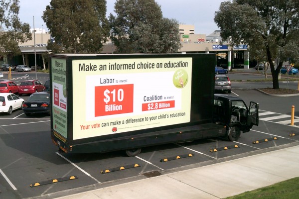 An Attractive Advertisement On A Mobile Billboard Truck Driving Down The Road Which Is About The Higher Education For Students.