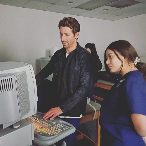 A technician teaching the student how to operate the ultrasound machine