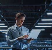 Portrait of a young male IT Specialist using Laptop in a Data Center.