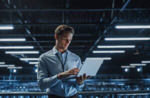 Portrait of a young male IT Specialist using Laptop in a Data Center.