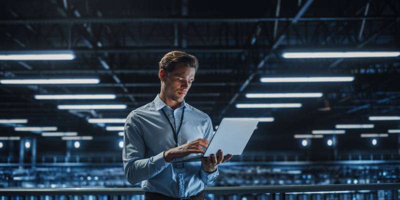 Portrait of a young male IT Specialist using Laptop in a Data Center.